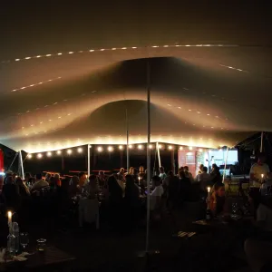 Cort festival de inchiriat Cort festival de inchiriat, Un cort extensibil închiriat la un festival, oaspeții savurând vin la lumina lumânărilor.